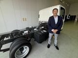 いすゞの専務執行役員/カーボンニュートラル戦略部門EVPの大平隆氏。エルフ EVトラックの技術展示車両と（筆者撮影）