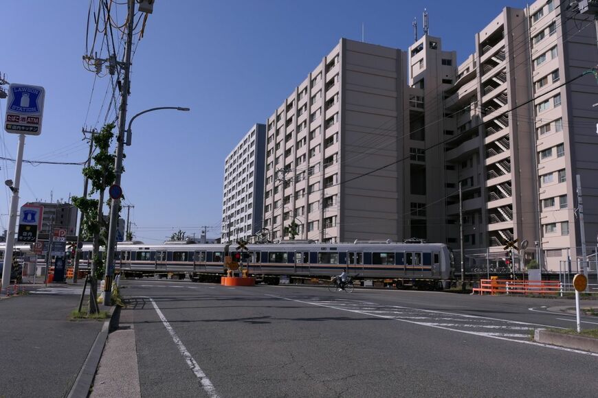 踏切を通過するJR和田岬線の電車。右の建物の奥に御崎公園がある（編集部撮影）