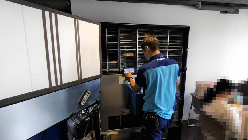 自動販売機に飲料を補充する様子。端末を確認しながら作業を進めている（筆者撮影）