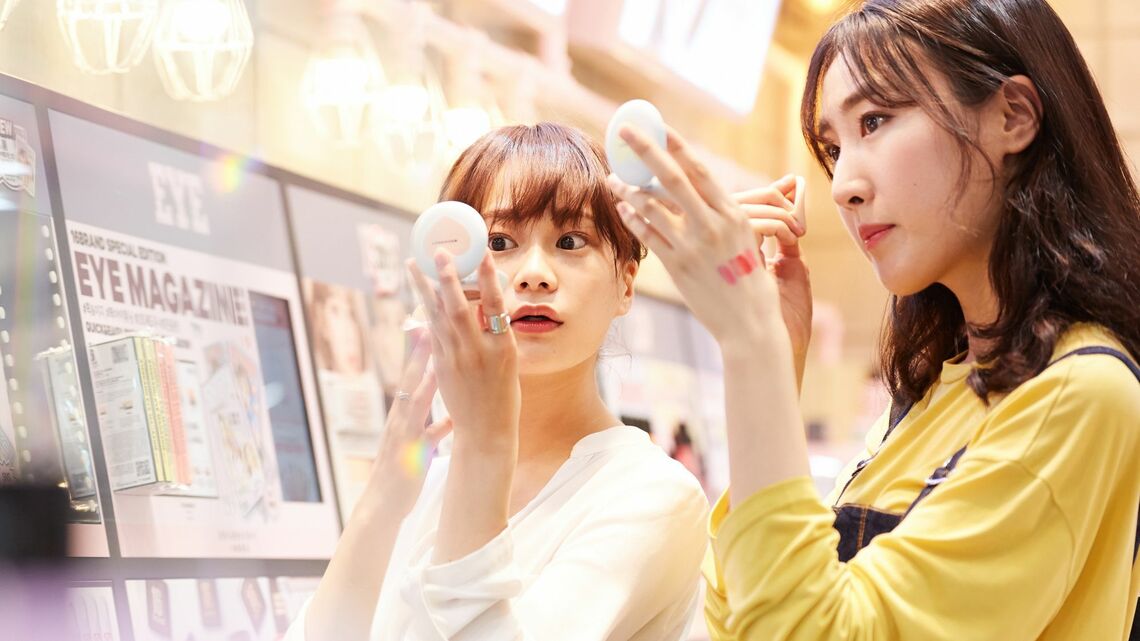 コスメ売り場で化粧品を試す若い女性