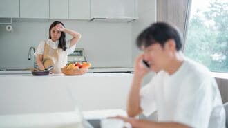 キッチンで料理する女性と仕事する男性