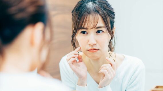 女性が鏡越しに肌の状態をチェックしている様子