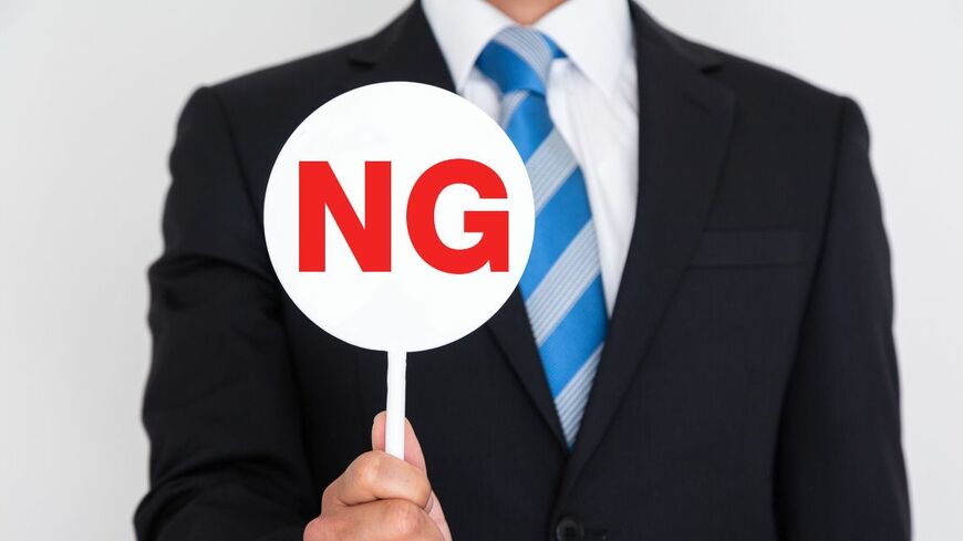 NGのプレートを持つスーツ姿の若者