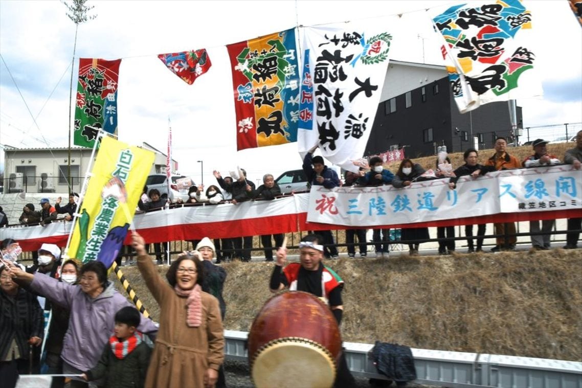 大漁旗を振って記念列車を歓迎する沿線の人々