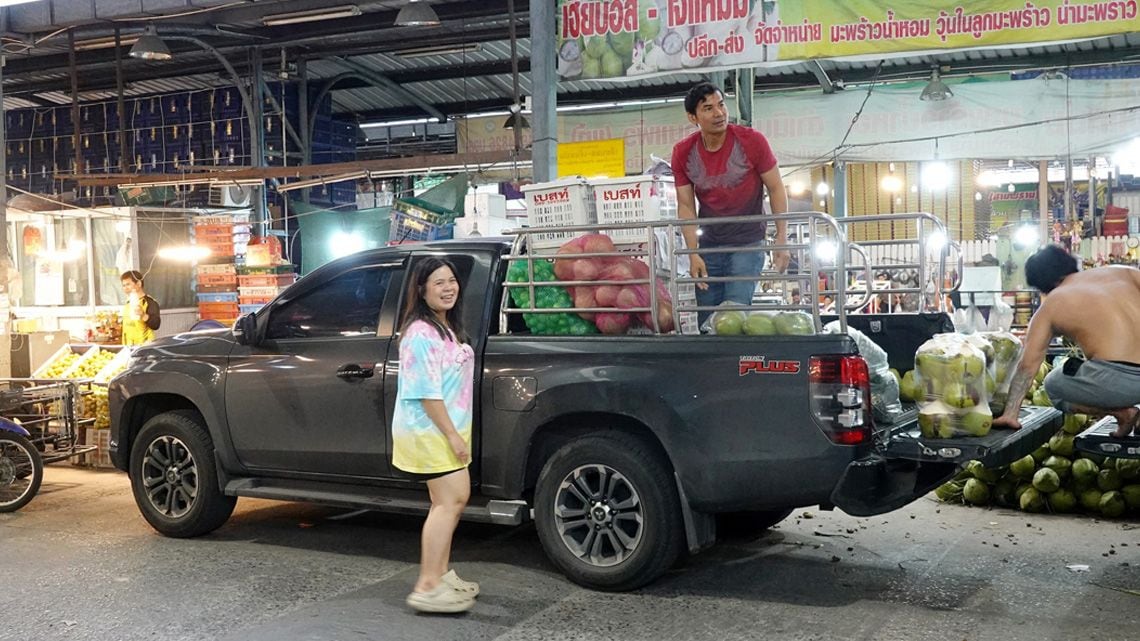 タイの市場でピックアップトラックに果物などを積み込む人たち