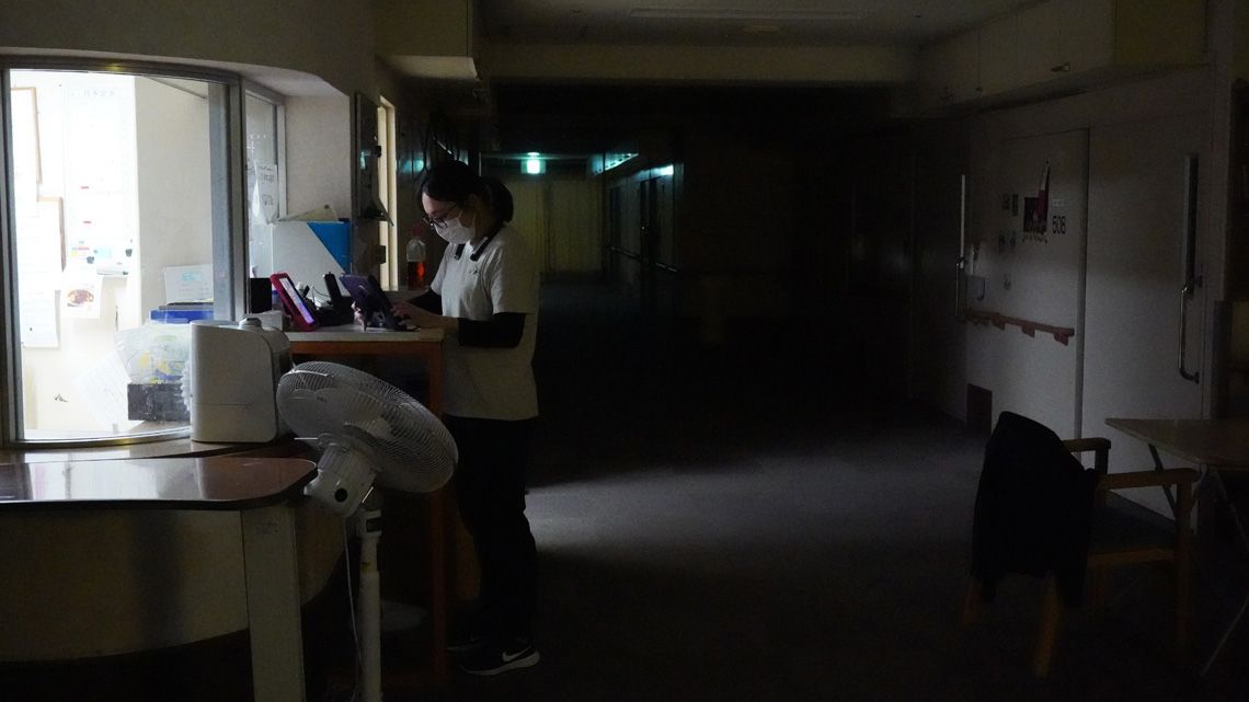 照明の落ちた施設内で勤務する女性職員