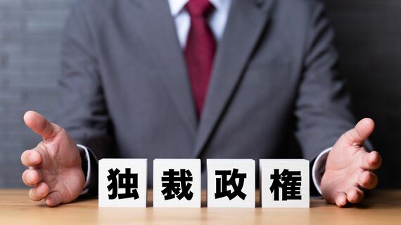 「独裁政権」と書かれたブロックとスーツを着た男性