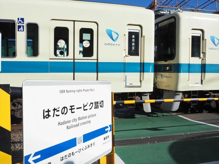 「はだのモーピク踏切」を通過する電車
