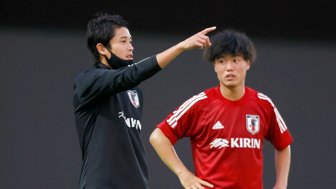 U-19日本代表合宿で選手を指導する内田篤人さん（左、写真：アフロ）