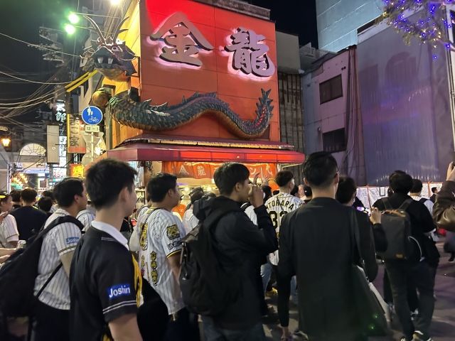 「金龍ラーメン」の横を通る群衆（写真：筆者撮影）