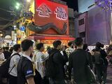 「金龍ラーメン」の横を通る群衆（写真：筆者撮影）