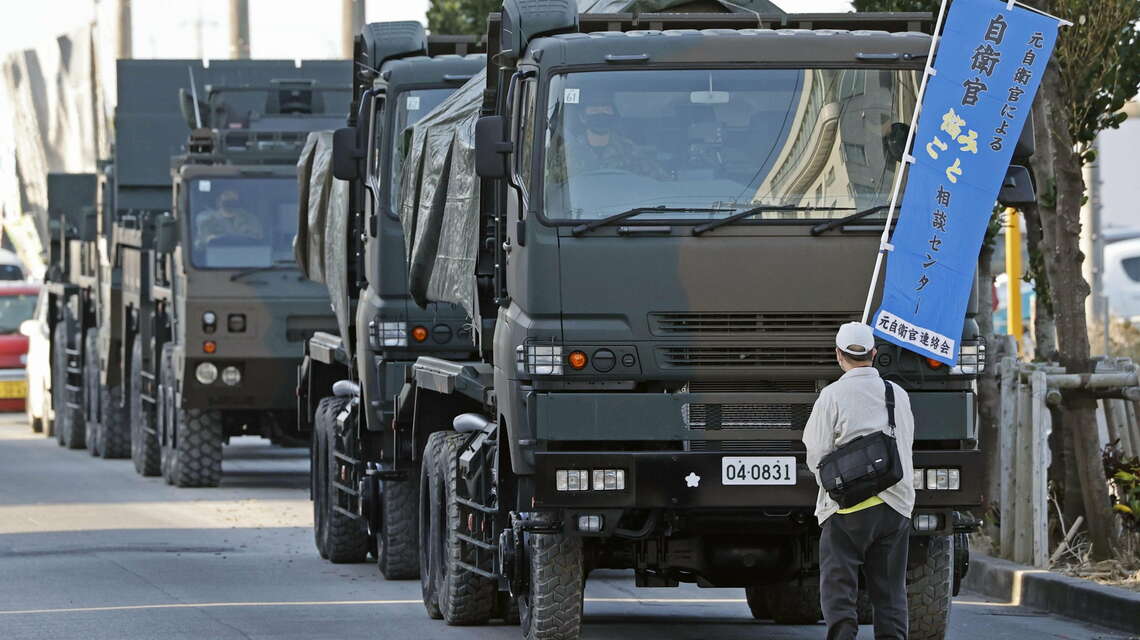 石垣駐屯地に向かう陸上自衛隊の車列に向かい抗議する人（写真：共同通信）