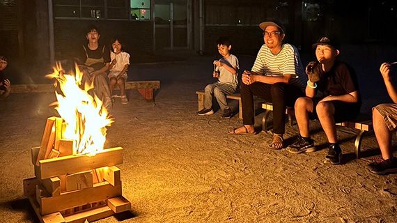 みんなで焚き火を囲んでマシュマロを食べている様子