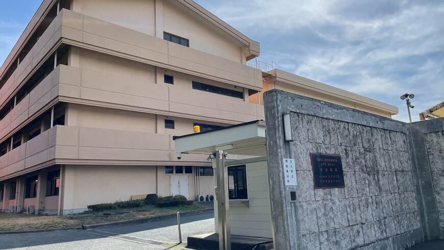 高い石壁に囲まれ要塞のような外観の神出病院。訪問者をサーチライトが照らし出す（記者撮影）