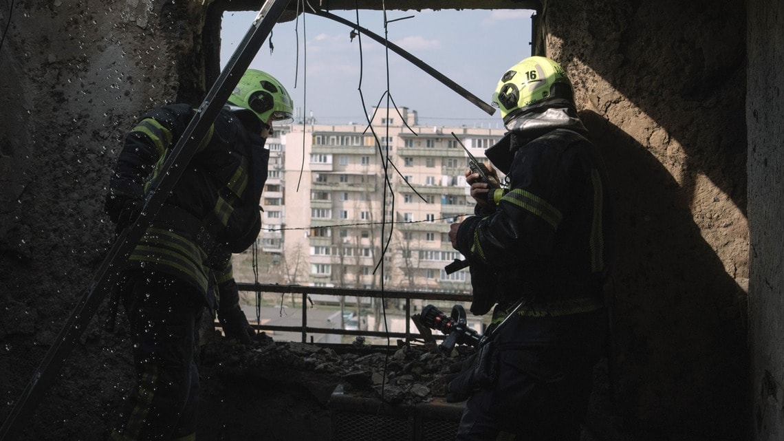 2025年3月23日、ウクライナのキエフで、ロシアの夜間無人機による空爆の後、消防士が住宅建物の被害を点検している。ウクライナのヴォロディミル・ゼレンスキー大統領は、3年前のロシアの全面侵攻で始まった戦争を終結させるためのドナルド・トランプ大統領の取り組みの第一歩として、エネルギー資産への攻撃を相互に停止する提案に同意した(写真・2025 Bloomberg Finance LP)