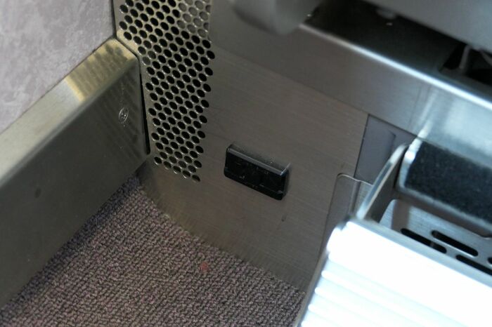フットレスト横の電源コンセント。パソコン・携帯電話用だ