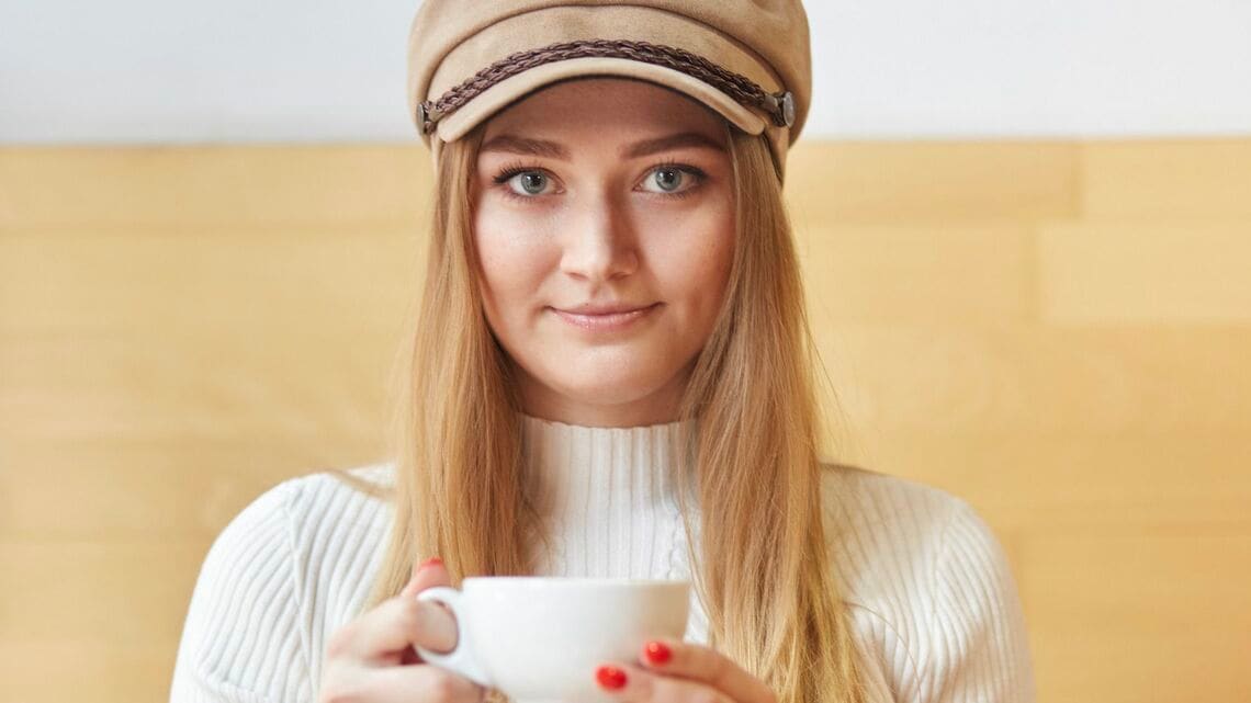 カプチーノを持つ帽子を被った女性