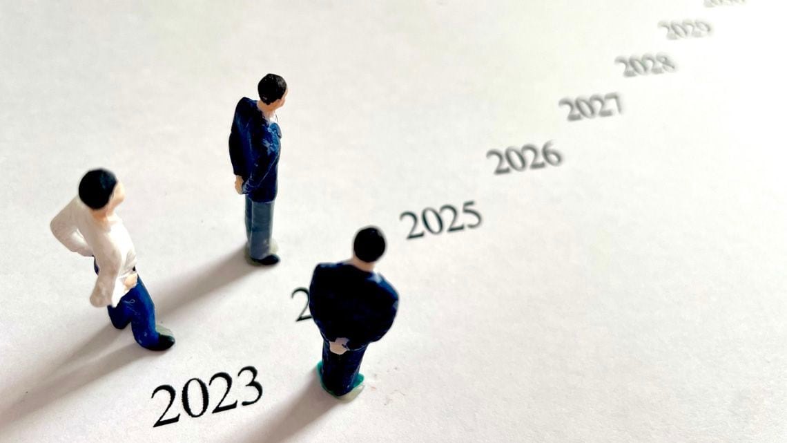 並んだ年号の2025年を見るビジネスパーソンのミニチュア