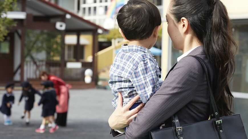 子どもを抱っこして保育士を見つめる母親