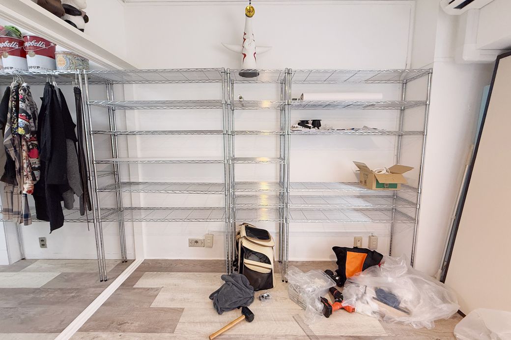 家の収納のほとんどをまかなう、薄型のメタルシェルフ。梁の高さぴったりサイズで組み立てた。奥行きが浅いものを選んで、少しでも居室が広くなるように努力（筆者撮影）