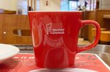 ロゴ入りのマグカップに注がれたミスド ブレンドコーヒー。マグカップは厚みとまるみのあるぽってりしたデザイン（筆者撮影）