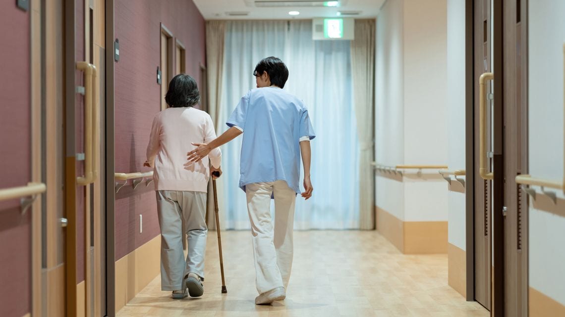 歩く高齢者を補助する介護職員