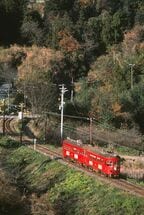 緑の中を走る赤塗装のモ510形とモ520形
