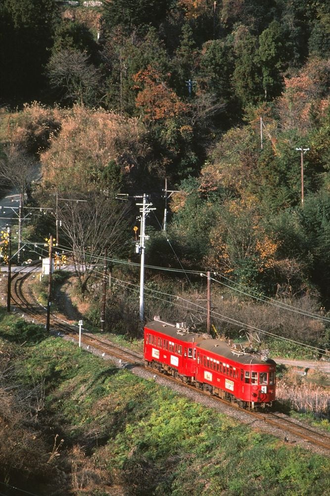 緑の中を走る赤塗装のモ510形とモ520形