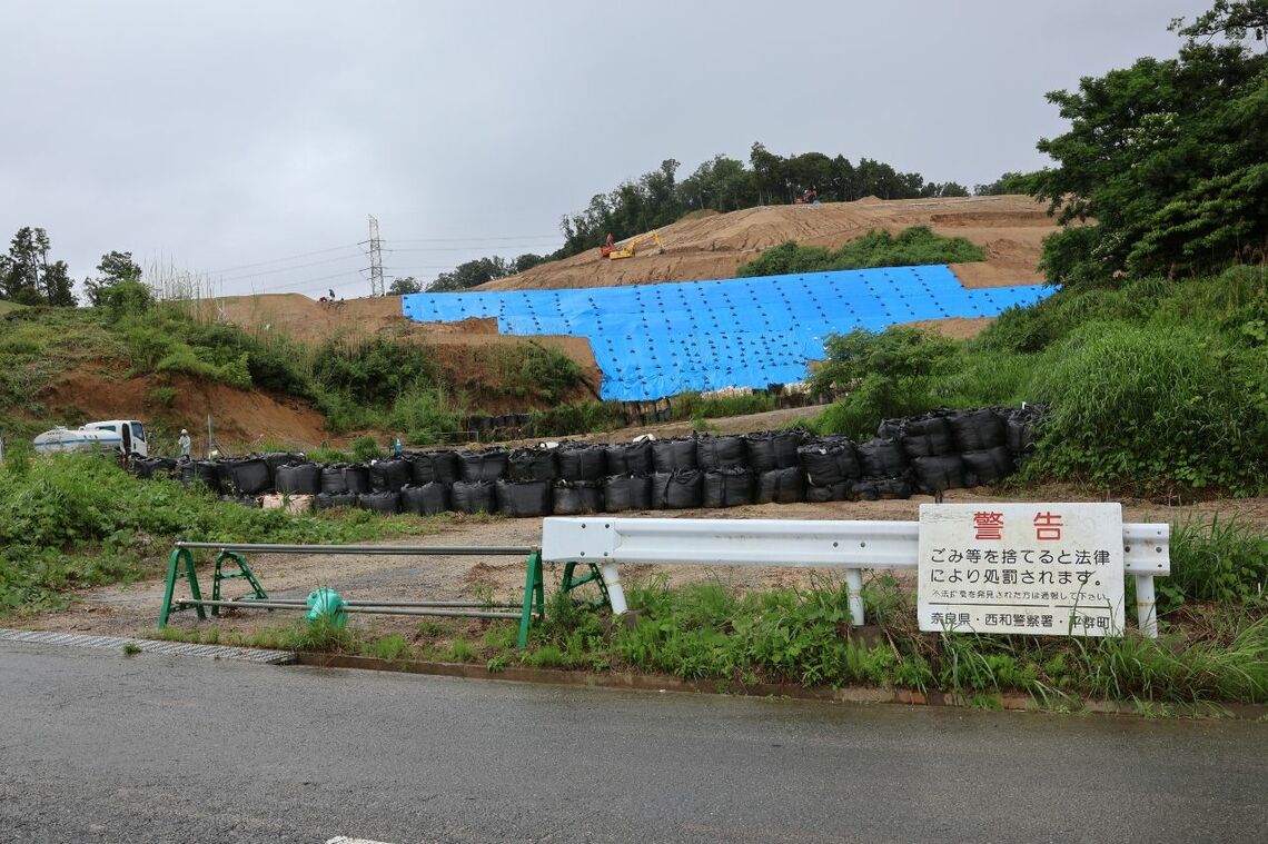 応急の対策工事が進む現場と、土砂が乗り越えたガードレール（撮影：河野博子）