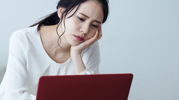 パソコンの画面を見て憂鬱そうな表情の女性
