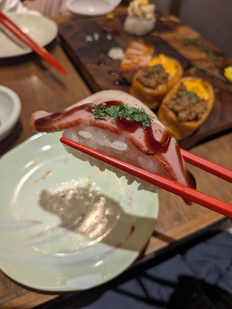 シャリの上に薄いベーコンをのせた「合鴨スモーク」（写真：筆者撮影）