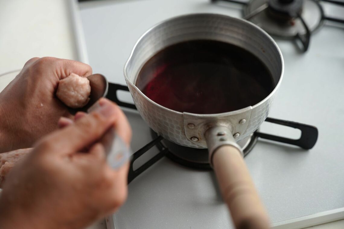 煮汁に鶏団子を落とす