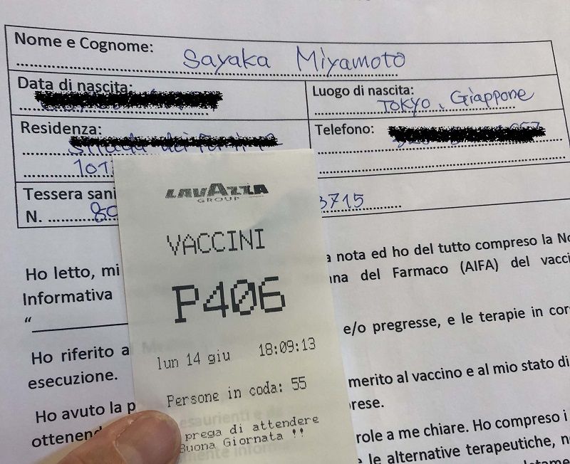 ダウンロードした接種票と当日会場でもらった番号札。何人が順番待ちをしているかが書かれ、最後に「よい1日を！」とあるのがイタリアらしい（筆者撮影）