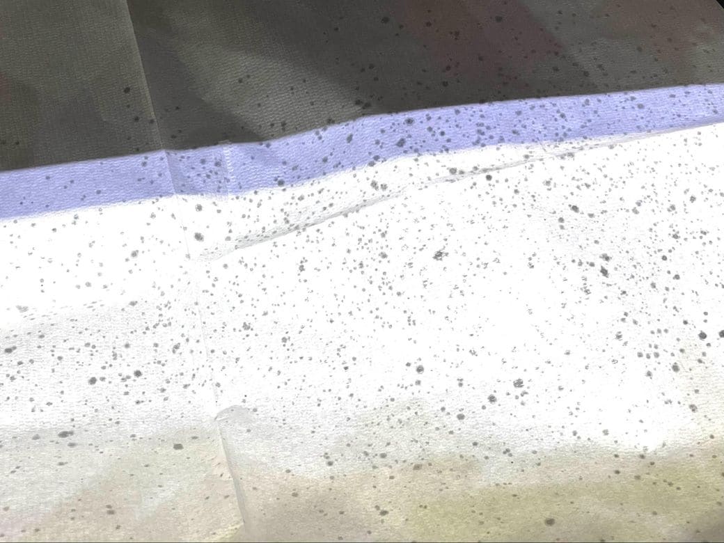 首から膝ほどまである紙エプロンは飛び散った油のシミがびっしりと（筆者撮影）