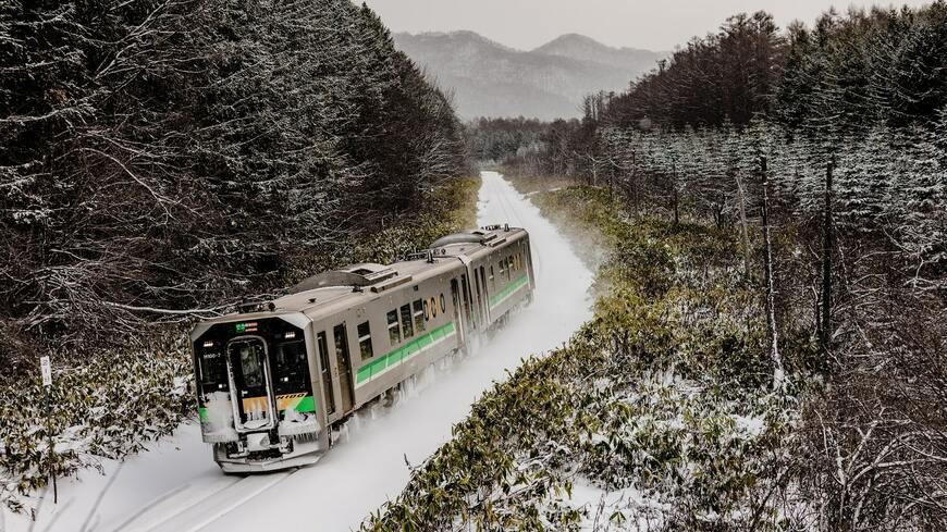 雪の中をゆく函館本線“山線”の電気式気動車「H100形」（撮影：鼠入昌史）