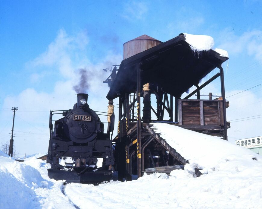 雪の会津田島駅にたたずむC11形。この254号機はデフレクター（除煙板）が通称「門デフ」と呼ばれる形態で、現在は会津田島駅前に保存されている（撮影：南正時）