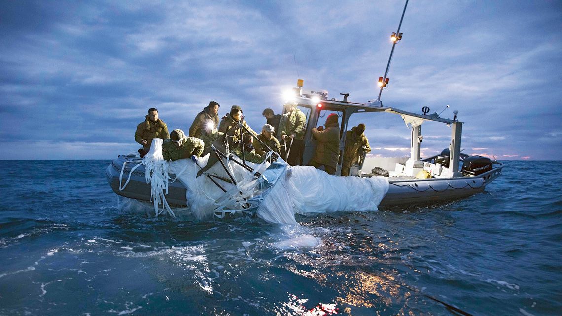 洋上で船に回収される気球の残骸