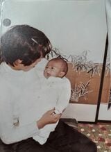 写真は1982年1月、0歳の長男・拓也をあやす知子さん（写真提供：佐藤さん）