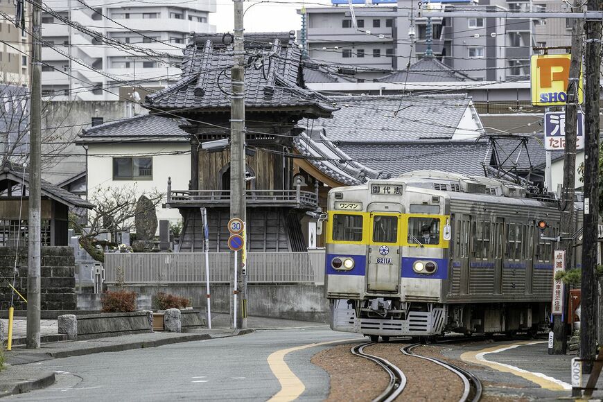 発車して600m走ると道路端の併用軌道に差し掛かる。 カラー舗装に見えるがそうではなく、バラストを網袋に入れて敷き詰めてある (藤崎宮前ー黒髪町間、写真：久保田 敦)