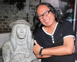「オロンガポの息子」の彫像の隣に立つフレディ・アギラ氏（写真・2012年11月、柴田直治）