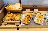 ジョナサンの朝食バイキング。左側には4種類のパンが並ぶ、右側には白身魚フライとハッシュドポテト（筆者撮影）