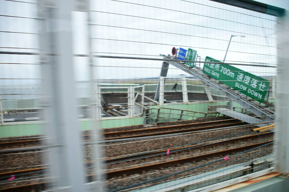 空港へのシャトルバス車内から見た空港橋のタンカー衝突部分。橋桁が線路に張り出し、道路標識が大きく傾いている（写真：traicy後藤卓也氏）