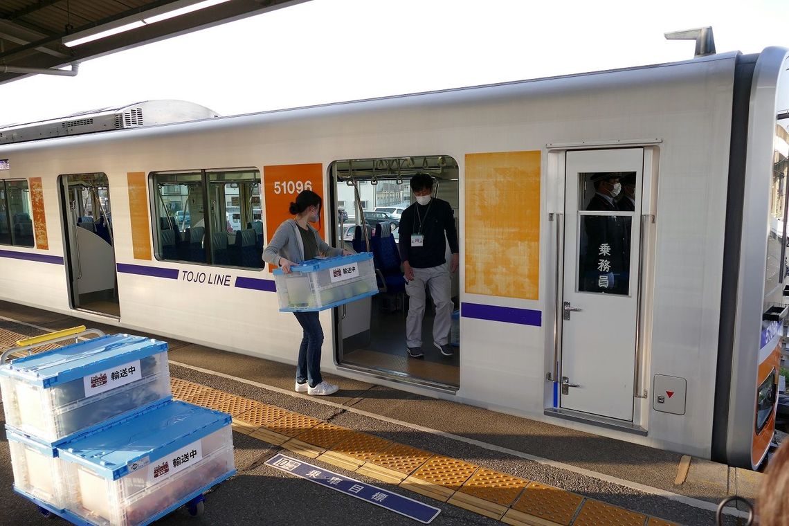 森林公園駅で電車内に積み込む（記者撮影）