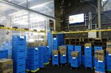 ダイドービバレッジサービスなにわ営業所の作業場。上部のモニターにはブロックごとの作業の進捗や遅れ時間などが掲示され、作業内容が見える化されている（記者撮影）
