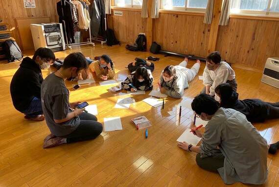 地べたで9人の人が話し合う様子