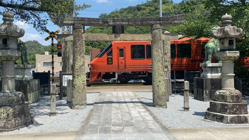 佐賀県有田町にある陶山神社の鳥居の前を走り抜ける特急ハウステンボス号（筆者撮影）