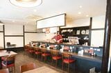 店内にはテーブル席とカウンター席が。調理風景も見えるようになっている。店の内装は、ラーメン屋の造りを参考に、女性ひとりでも気軽に入れる雰囲気を大切に考えたという（筆者撮影）