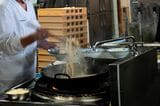 中華鍋の隣では麺が茹でられている。どんぶりに茹で上がった麺が入り、その上に具材が山盛りによそわれていく。野菜の量は計っておらず、目分量だという（筆者撮影）