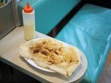 いか焼き（220円）。小麦粉を溶いた生地の中に刻んだイカを入れて焼き上げる粉もん料理の一種。もちもちの薄い生地に、甘辛い特製ソースがじんわり絡む。容器ごと渡してくれるマヨネーズで味の調節をしてもいい。いか焼きは玉子・野菜が詰まったデラックスなど全4種類（筆者撮影）