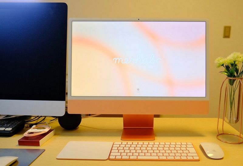 iMac 27インチ（Intelモデル、左）との比較。ディスプレーの額縁が小さくなり、小型化が際立っていることがわかる。正面からAppleロゴはなくなった。また付属するキーボードやマウスも、ボディカラーに揃えられている（筆者撮影）